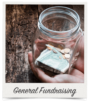 A hand holding a glass jar with some change and cash against a wooden background, labeled General Fundraising.